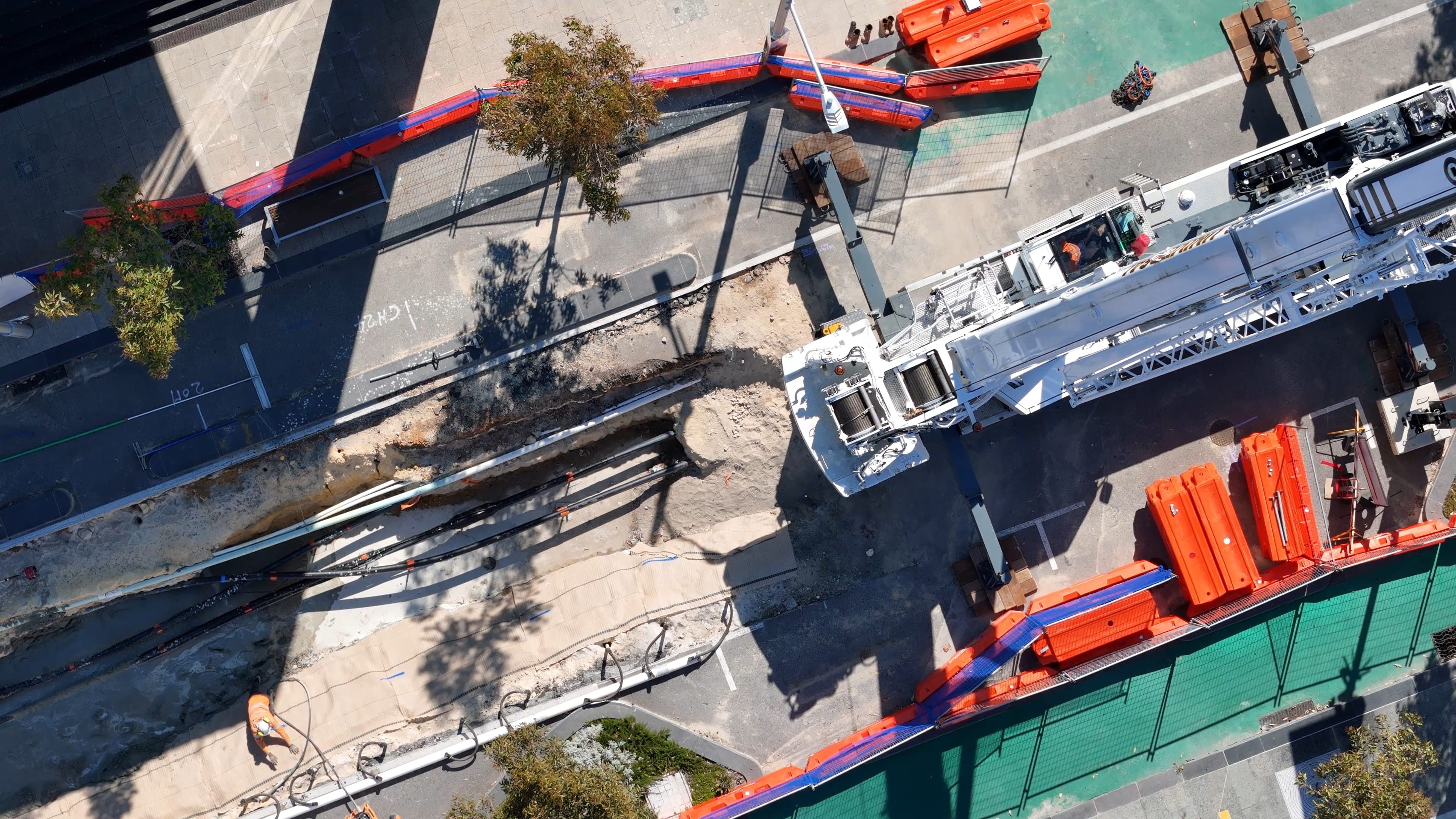 Aerial view of a Benang crew and crane working an open service trench along a suburban street