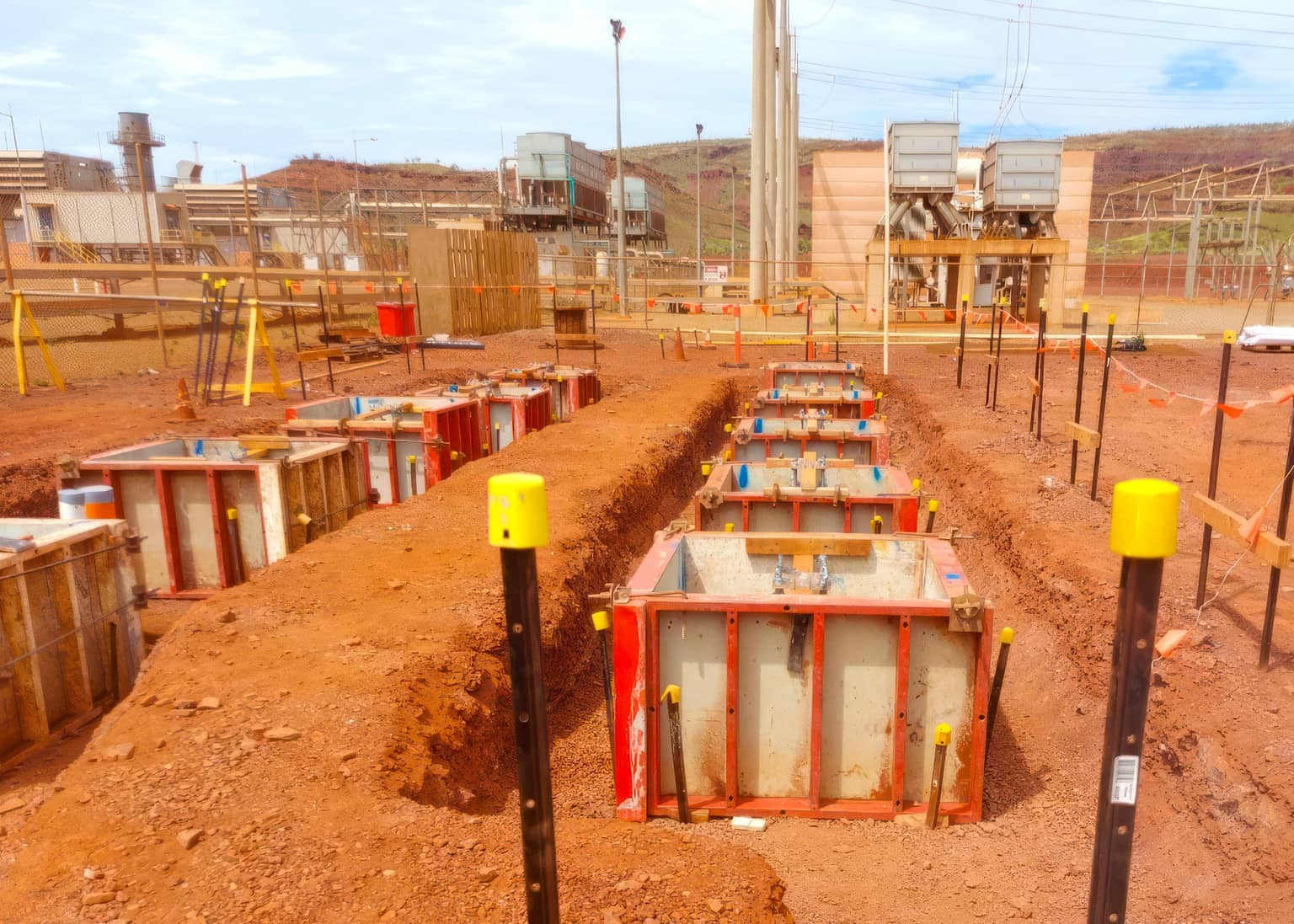 Formed footings lined out across the red dirt pad