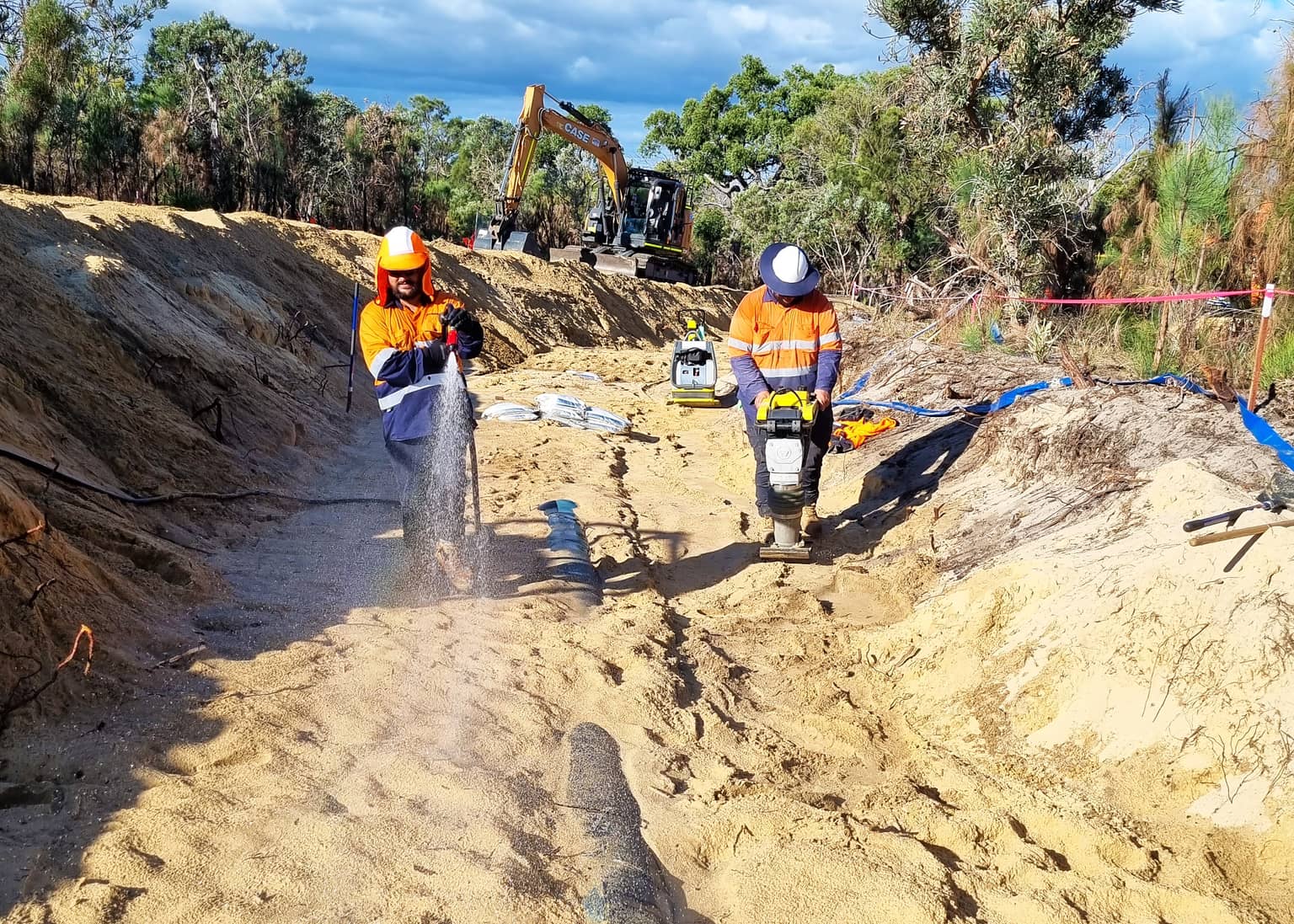 Crew compacting backfill over the new main
