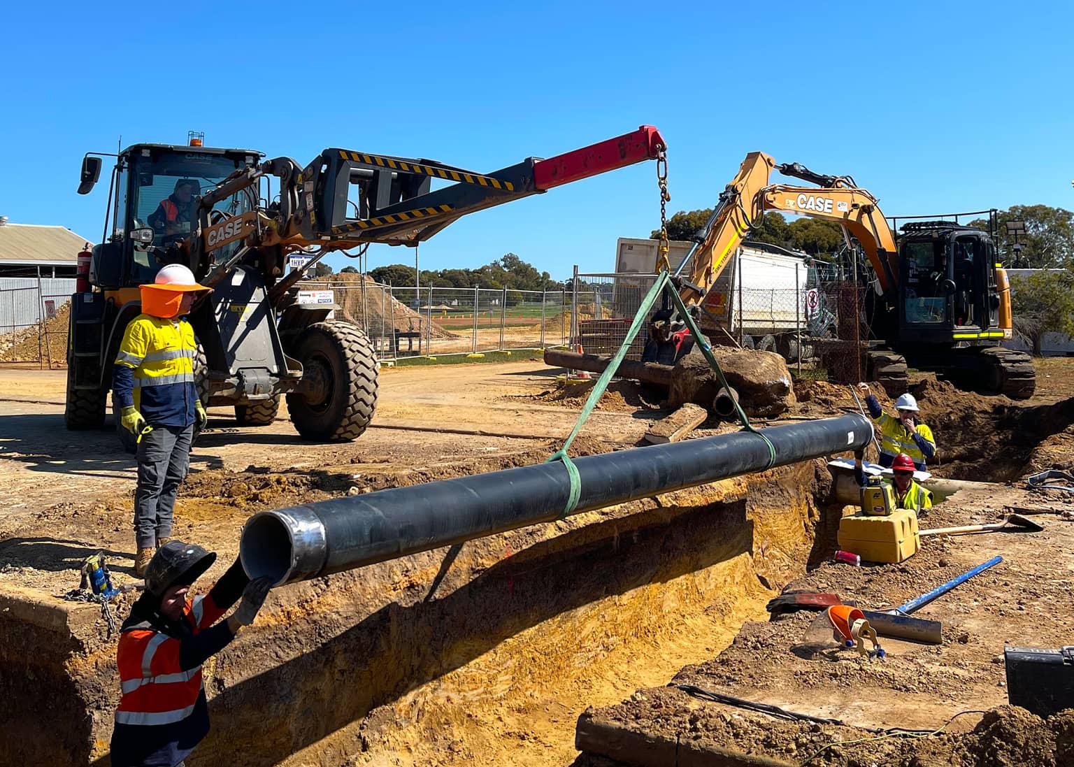 Benang crew lowering a pipe section into position with an excavator