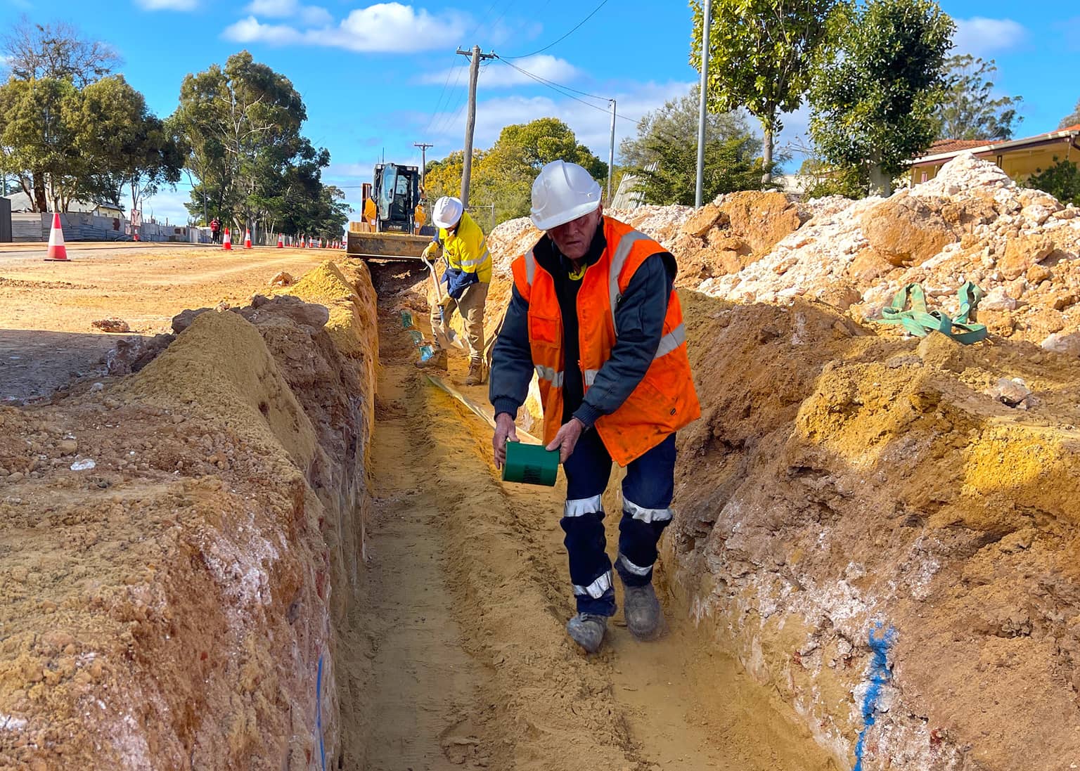 Benang worker placing pipe bedding in the trench