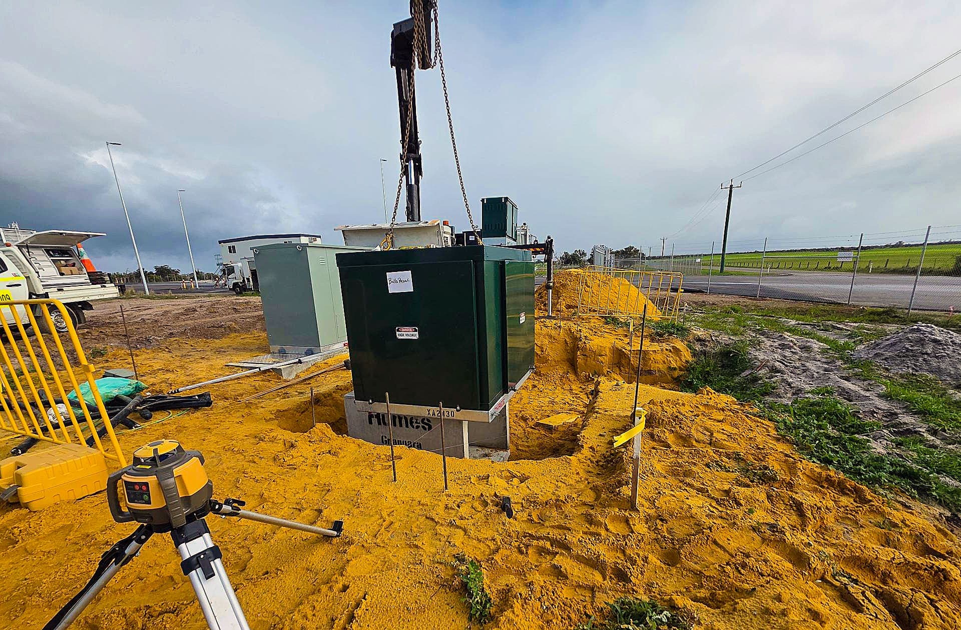 Crane lowering the green kiosk substation into position beside the road at Bullsbrook