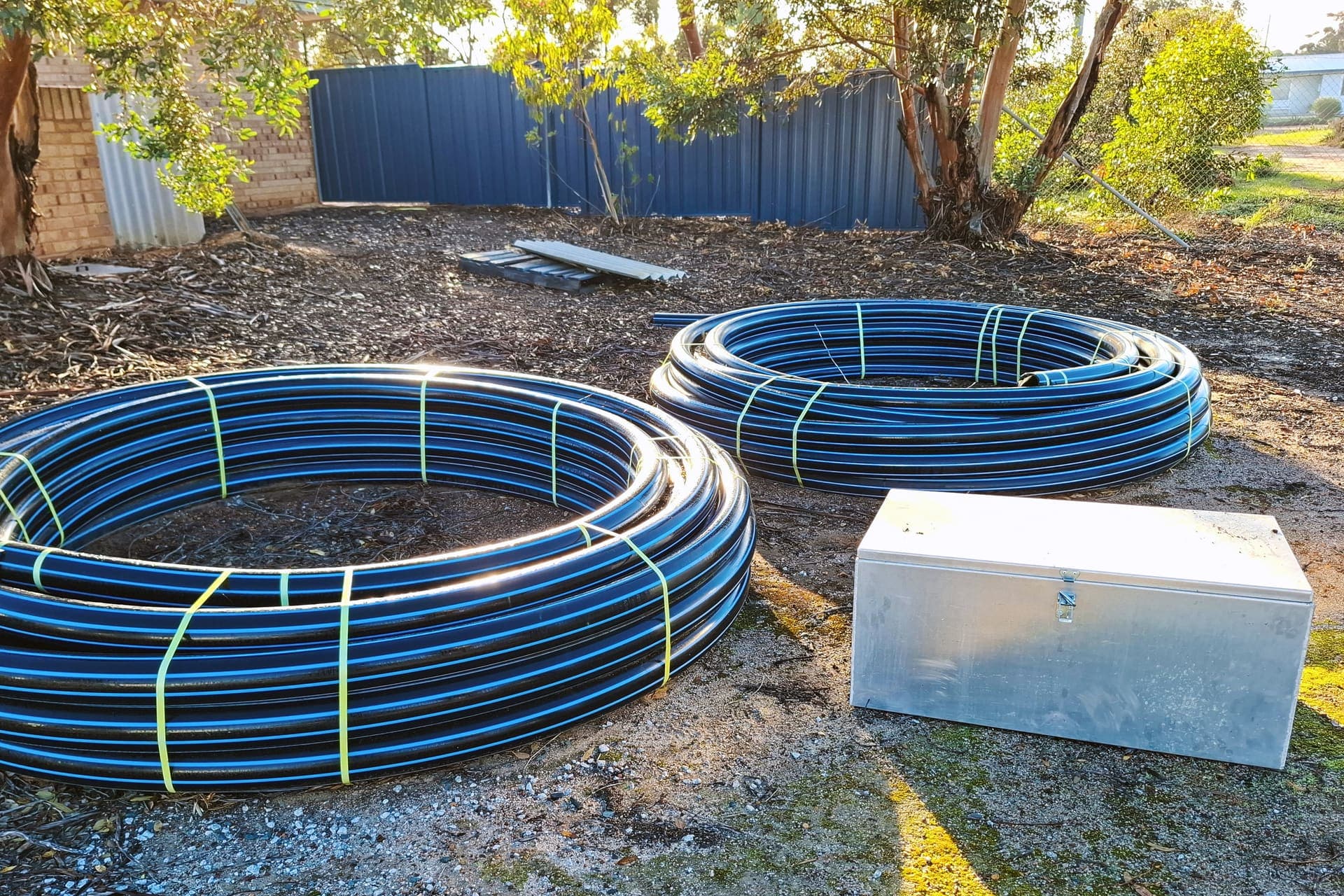 Coils of HDPE poly pipe and a stainless cabinet staged for installation at Lake Grace