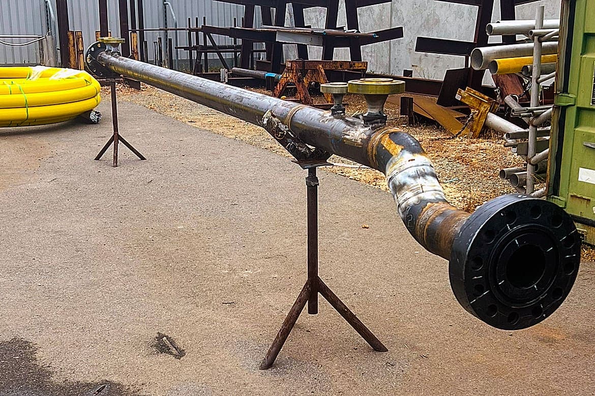 Carbon steel pipe spool with painted flanges resting on trestle stands in the Benang yard