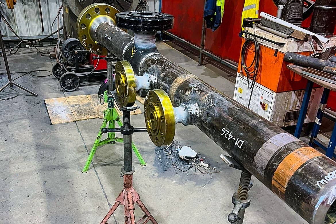 Carbon steel pipe spools with gold flanges on jack stands in the Benang workshop