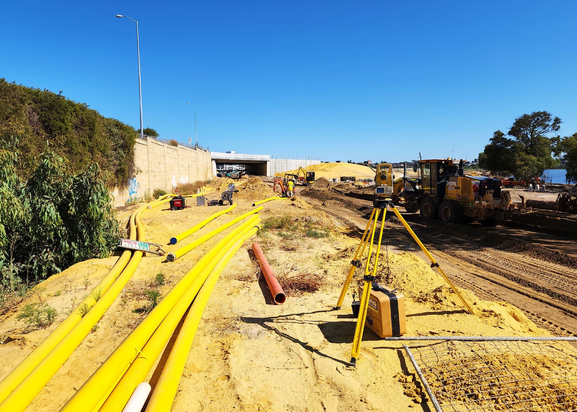 Yellow gas mains strung out along the river foreshore route towards the underpass near Belmont Park