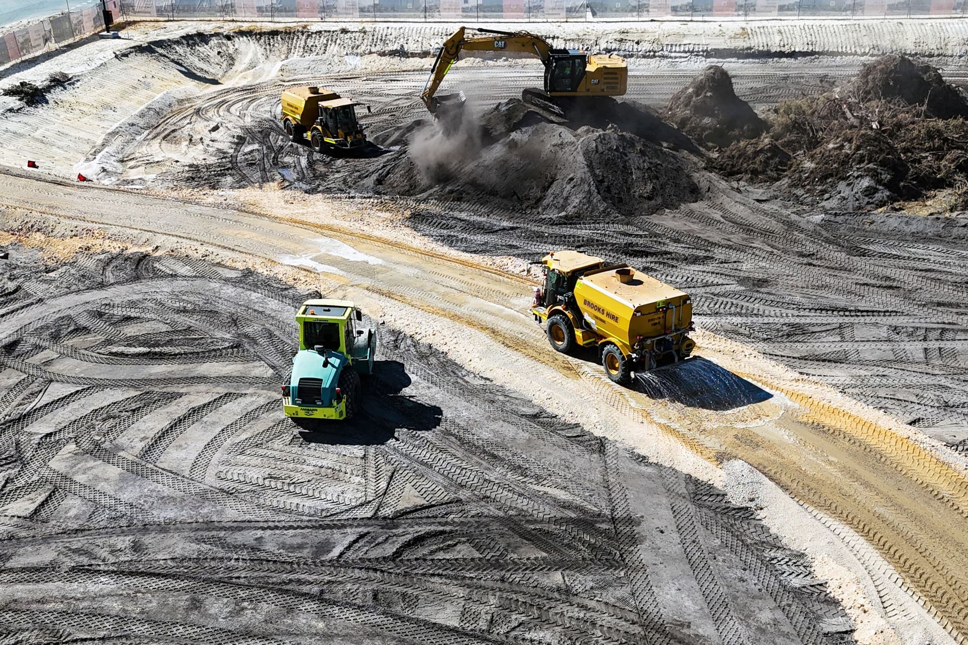Roller, water carts and excavator working across the stripped earthworks pad at The Parkway