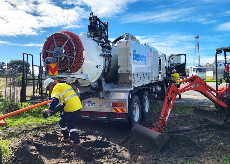 Benang dry-vac excavation truck and excavator exposing underground services, with orange conduit reel loaded