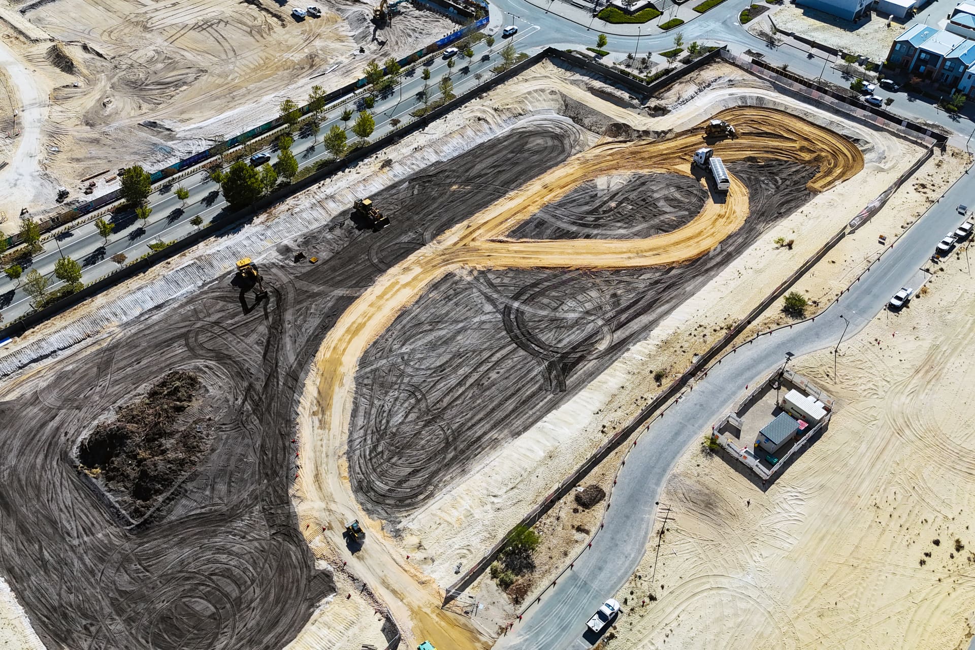 Aerial view of the Lot 29 earthworks at The Parkway, Ellenbrook, with stripped ground, a sand haul road and Benang machines at work