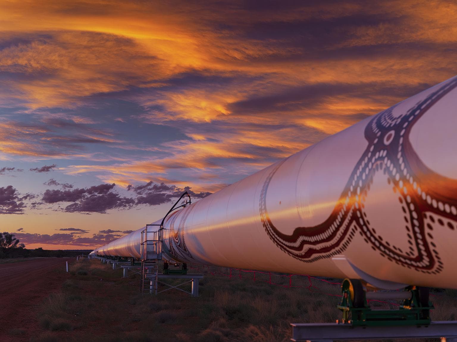 Large pipeline with Aboriginal artwork in the Western Australian landscape at sunset