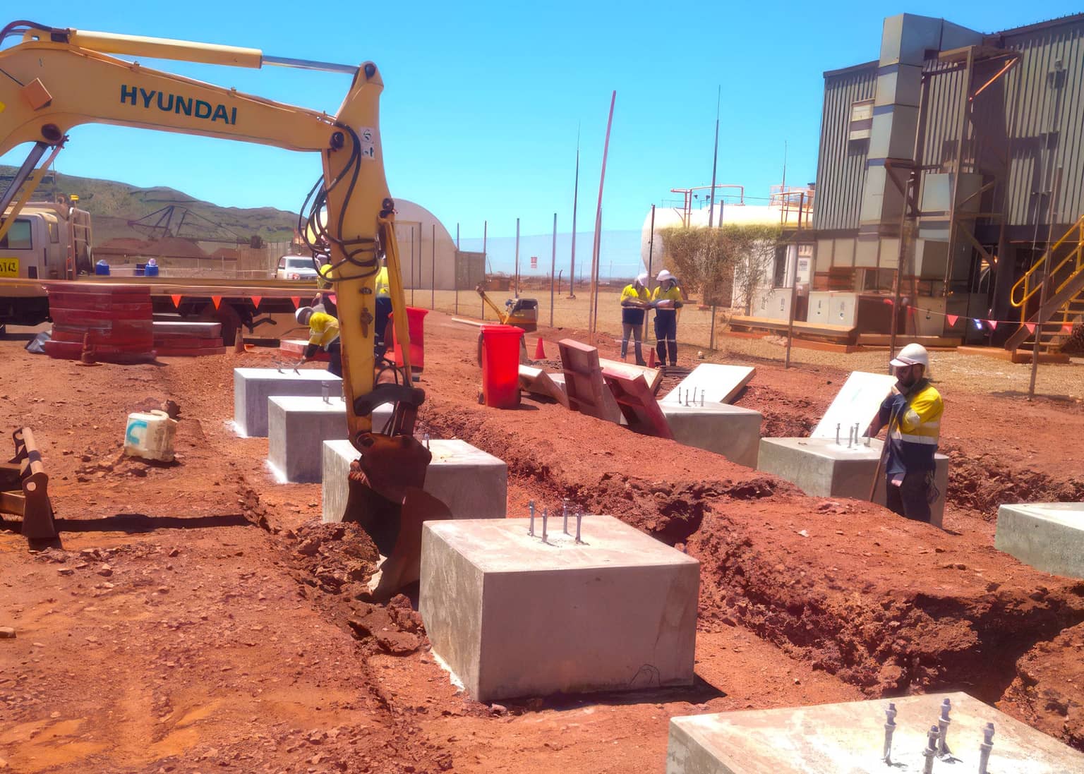 Excavator placing precast footings for the power installation