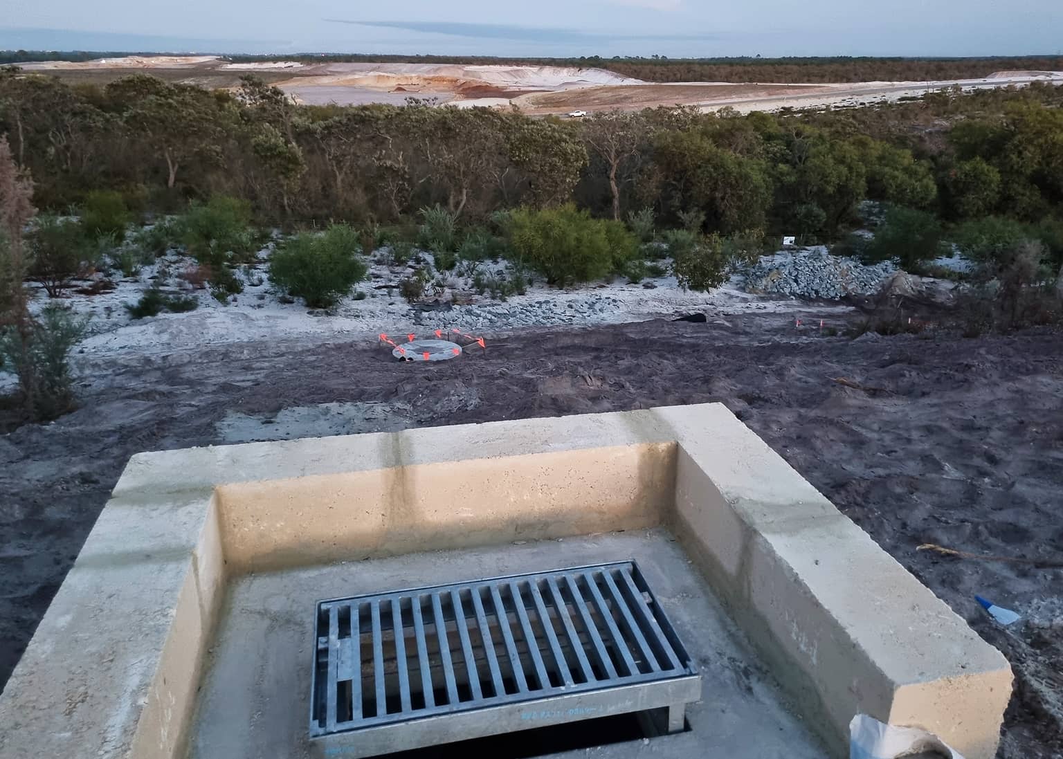 Concrete drainage structure overlooking the cleared site