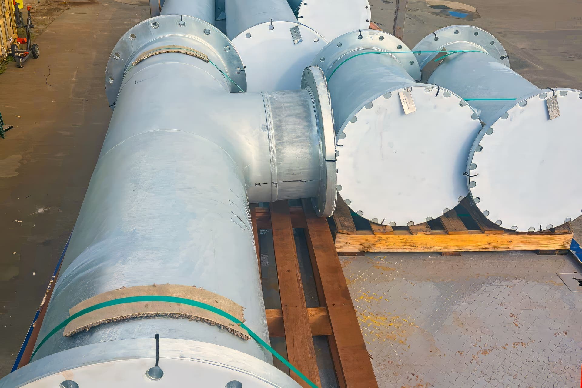 Large galvanised flanged pipe spools stacked on timber pallets in the Benang yard
