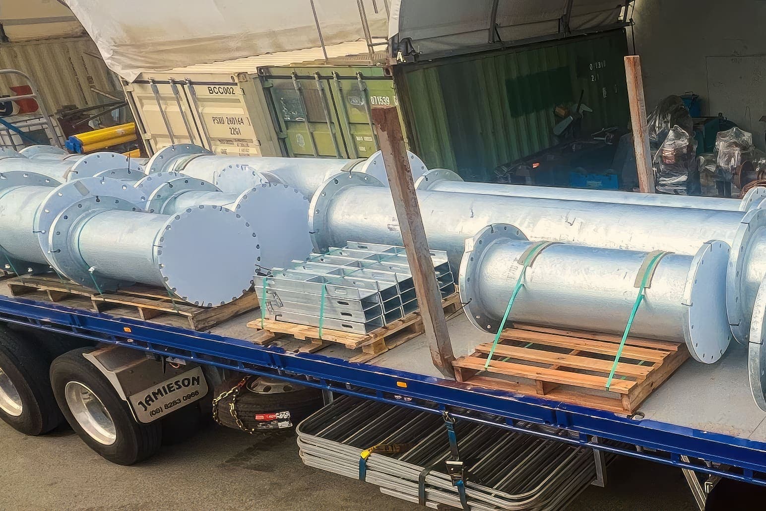 Galvanised pipe spools and cable tray bundles loaded on a flatbed truck for delivery