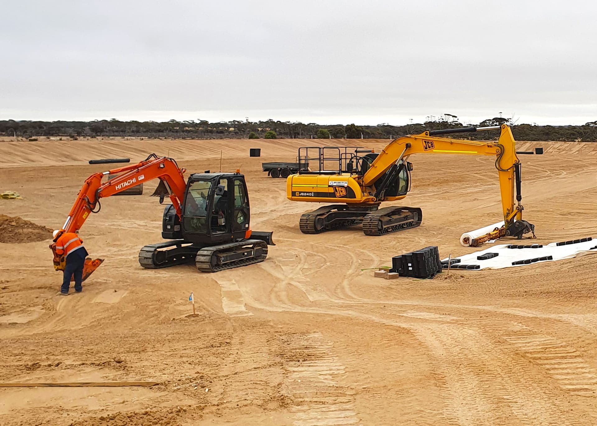 Two excavators lining the new effluent storage pond with geofabric and blocks at the Hyden wastewater treatment plant