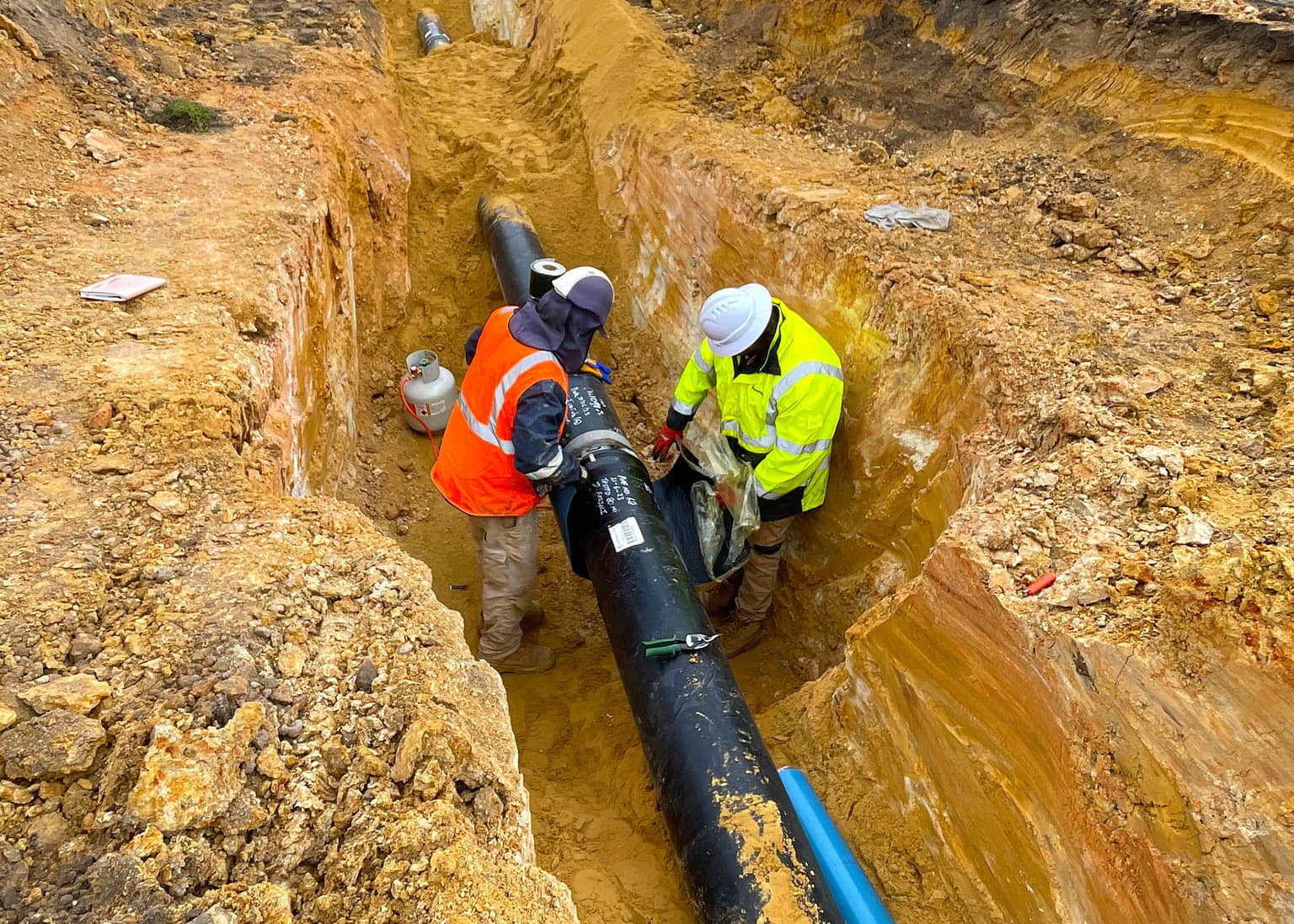 Two Benang crew guiding a DN300 pipe section into the trench at Katanning