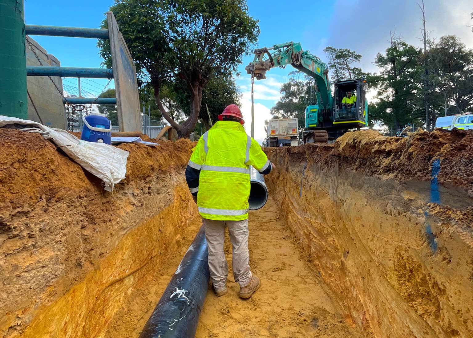 Benang worker walking the trench line beside the laid DN300 main
