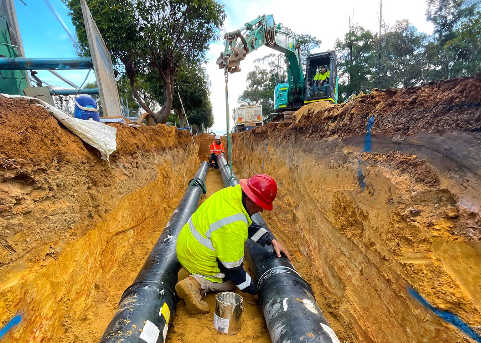 Worker finishing a pipe joint in the trench