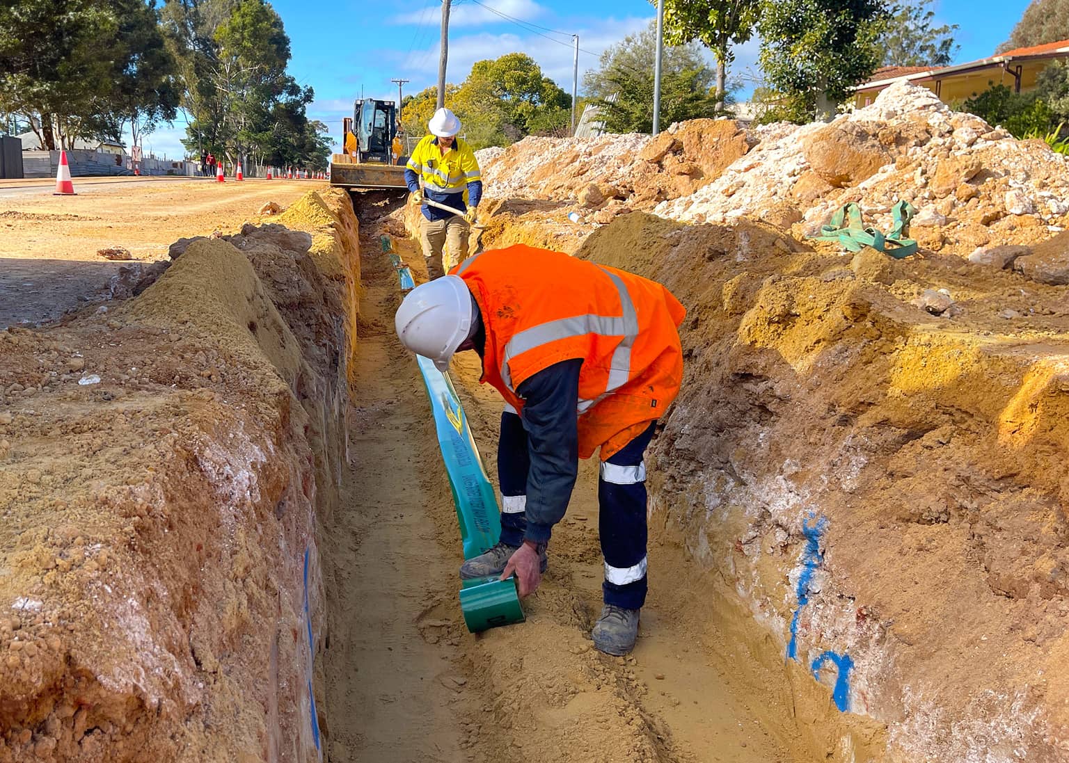 Benang worker preparing the trench floor for pipe laying