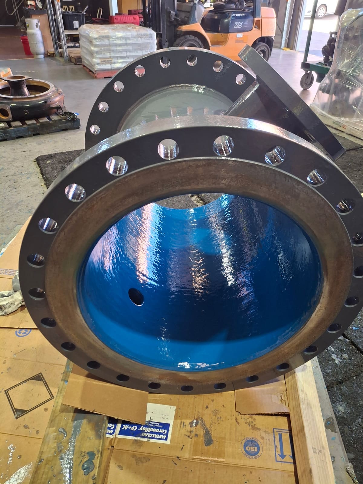 Coated carbon steel spool strapped to a pallet for transport