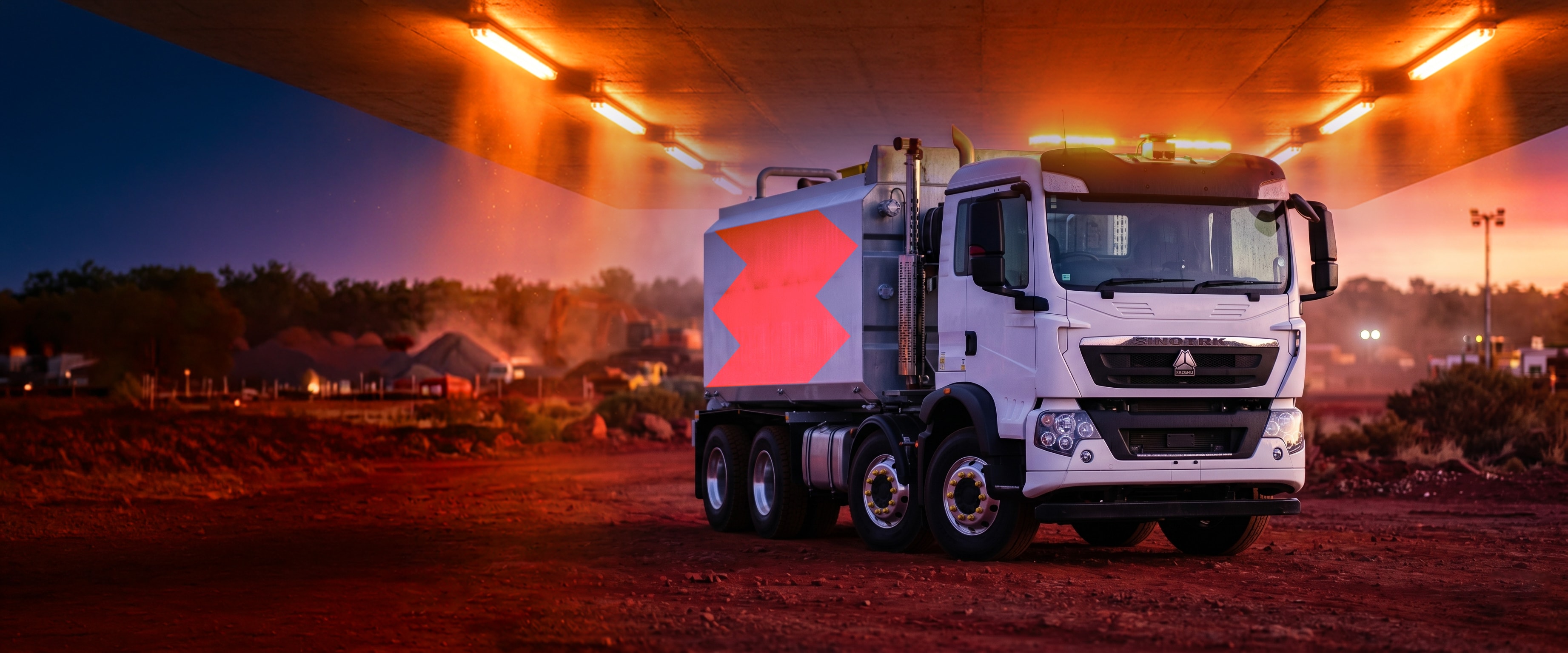 Benang water truck with the orange Benang symbol parked under a highway overpass at dusk